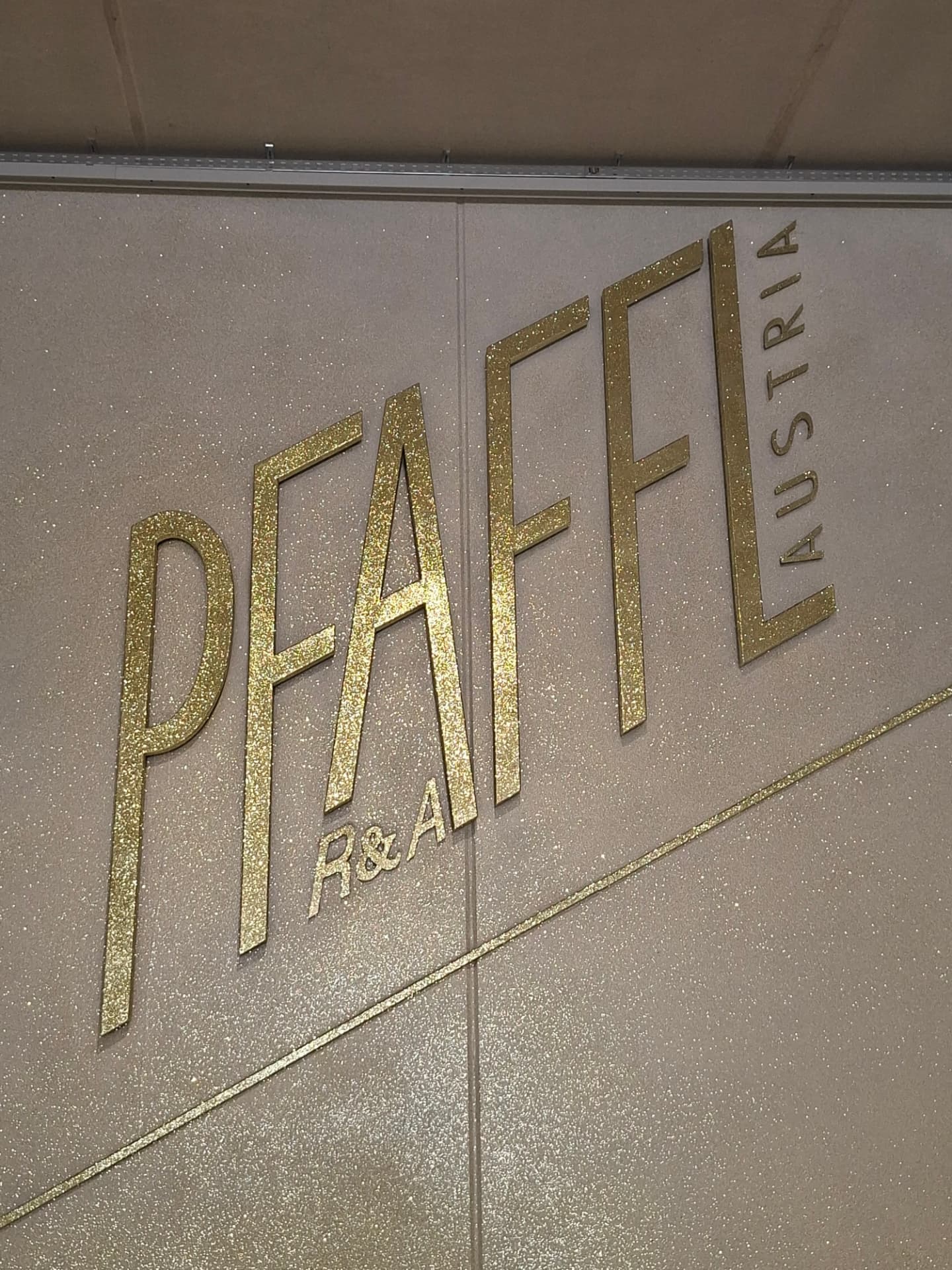 Goldenes Pfaffl-Logo auf der Chips-beschichteten Wand